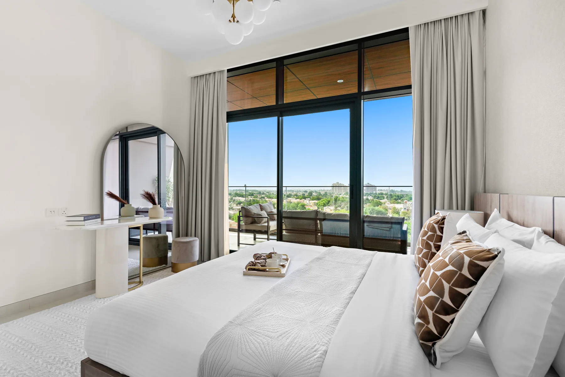 A bright bedroom with a large bed and glass doors opening onto a balcony.