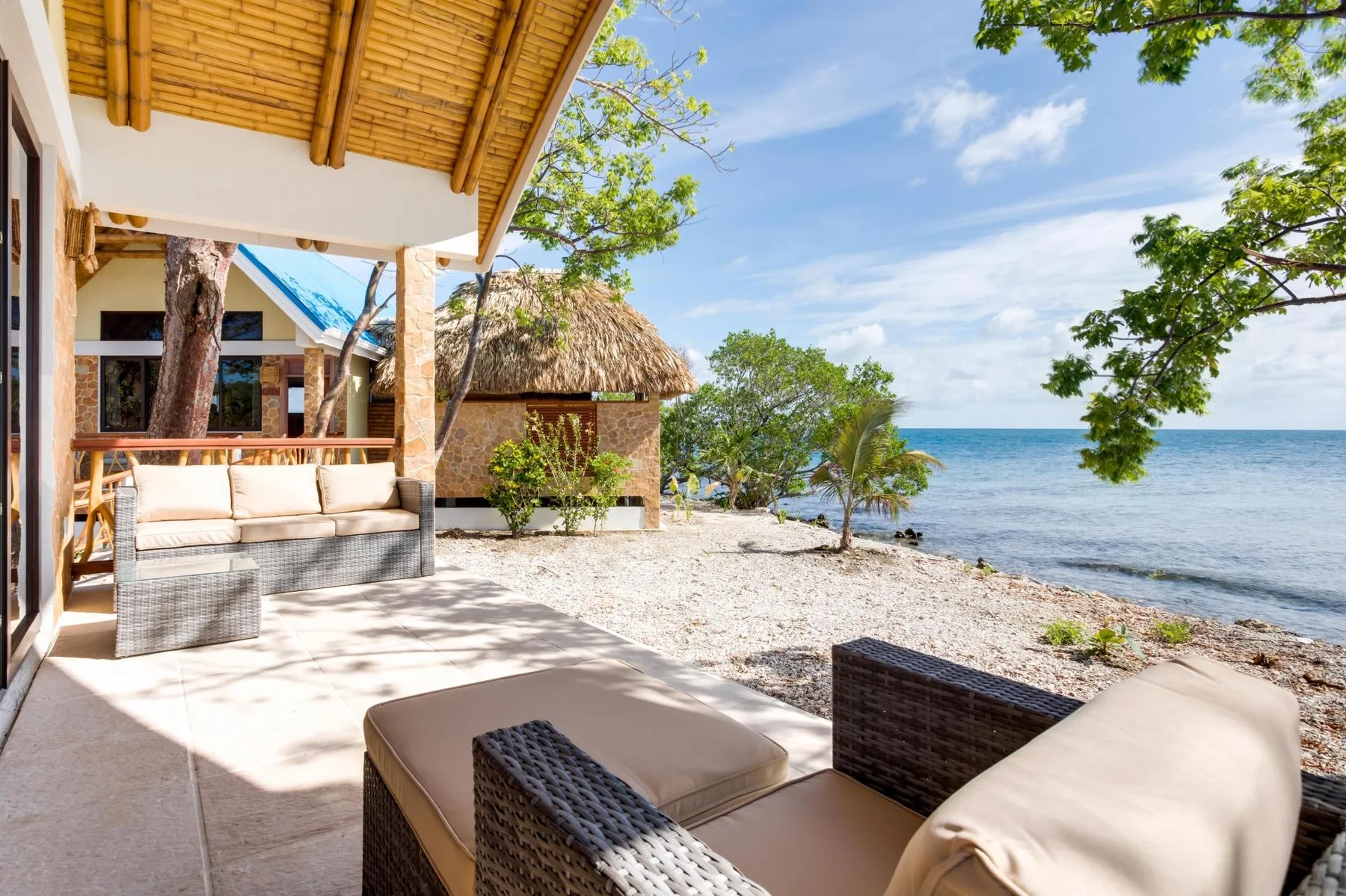 A beachfront patio with cushioned seating overlooks the ocean.