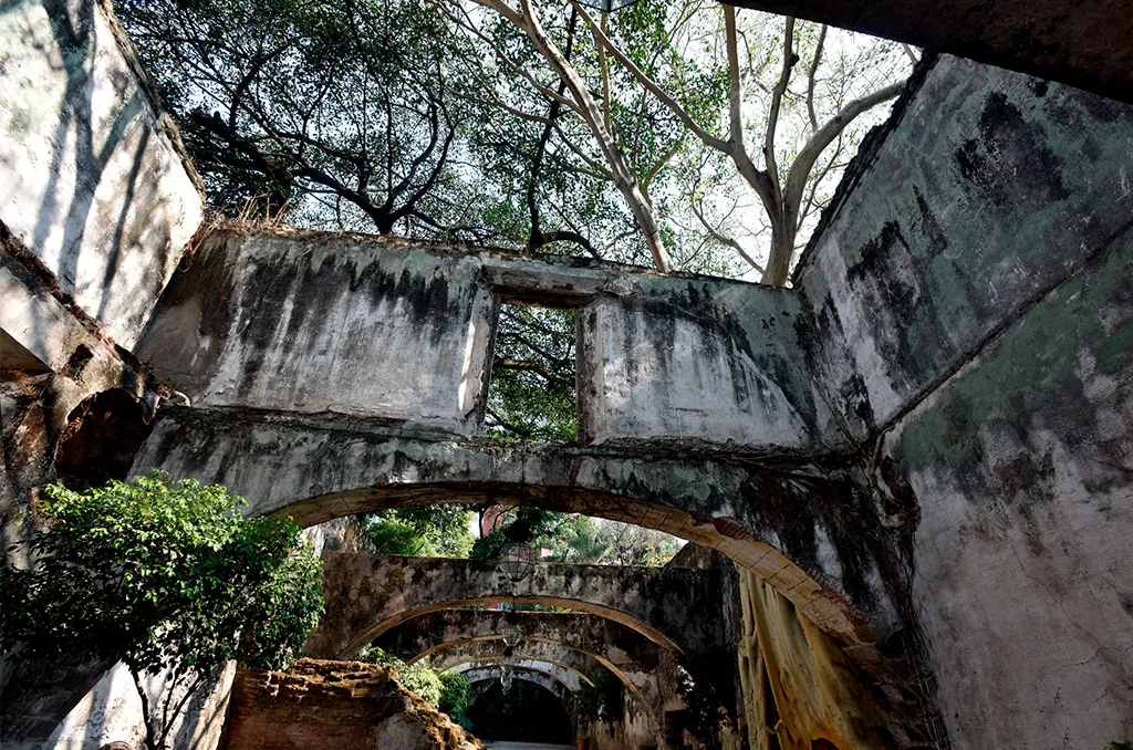 Espacio representativo del hotel: Estructura de piedra en ruinas con una serie de arcos bajo los árboles.
