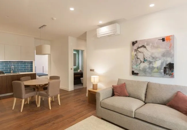An open-plan living and dining area with a sofa, dining table, and kitchen.
