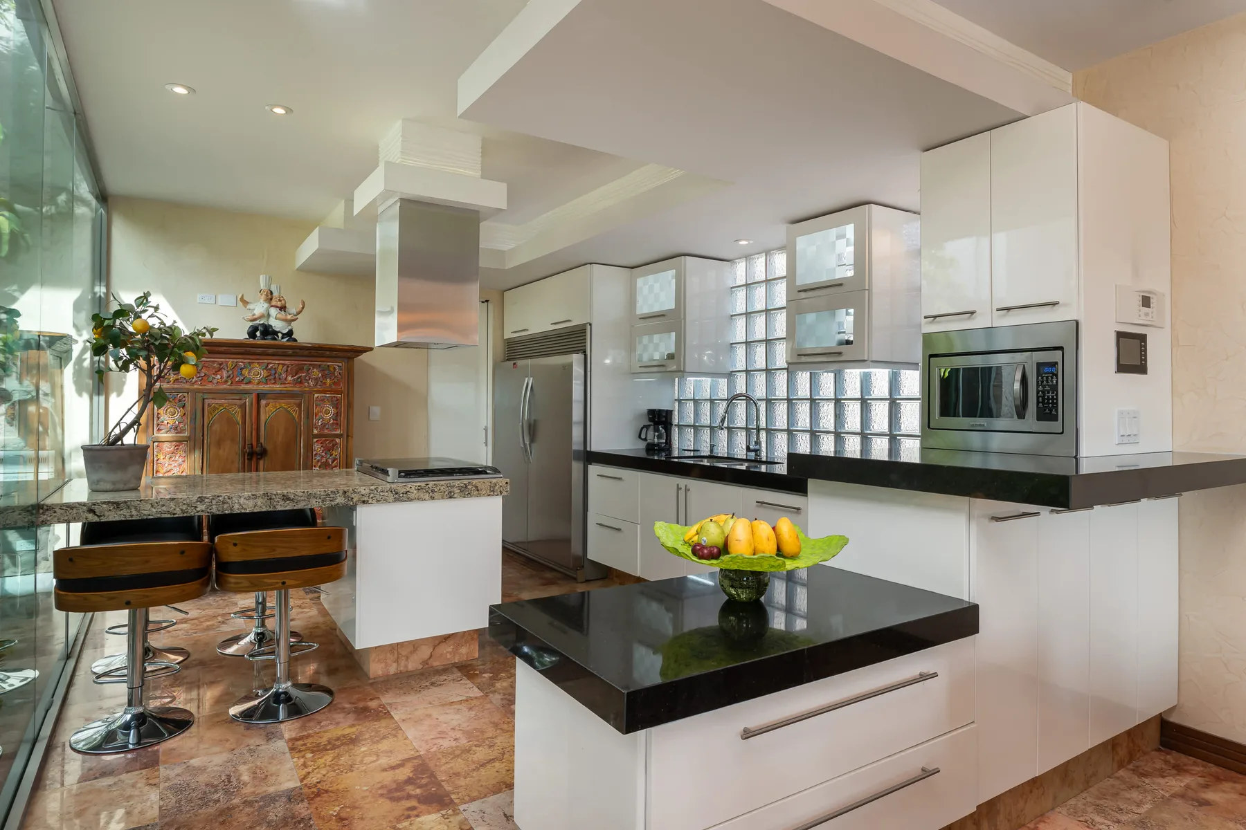 A modern kitchen with white cabinetry, dark counters, and a central island.