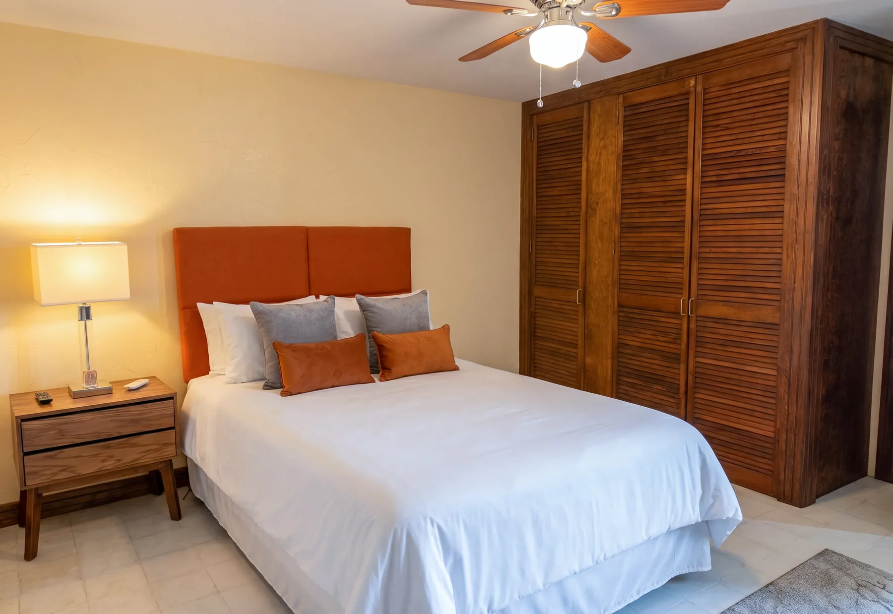 A bedroom with a bed, bedside table, and wooden louvered closet doors.