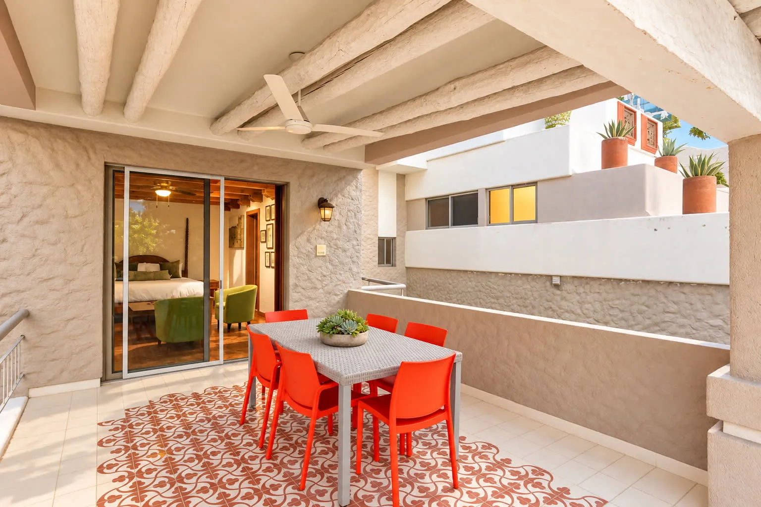 A tiled outdoor dining area with a table and bright red seating.