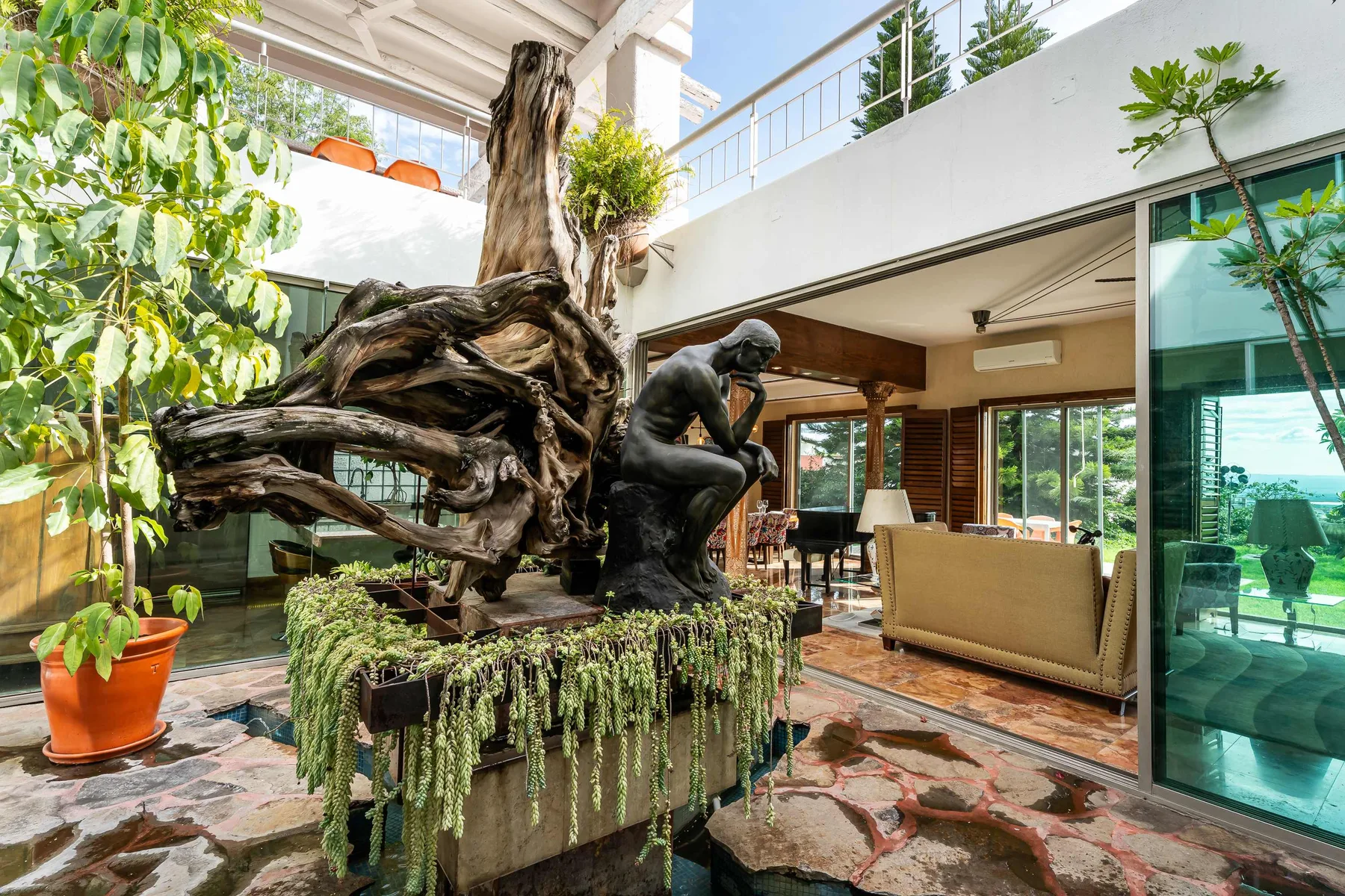 An open-plan living area features a sculptural tree and a seated figure.