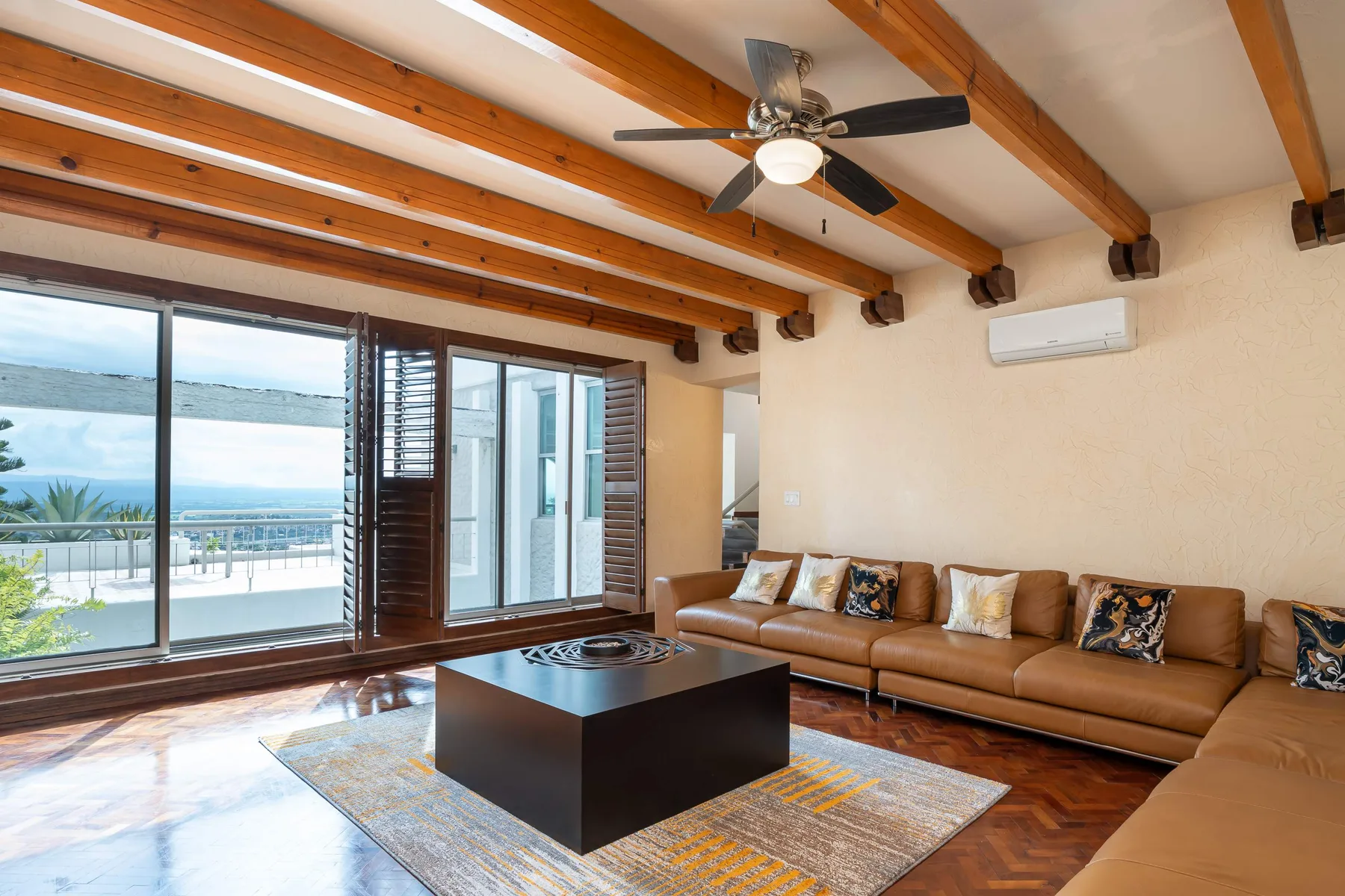 A living room with a brown sectional, coffee table, and ocean views through wide windows.