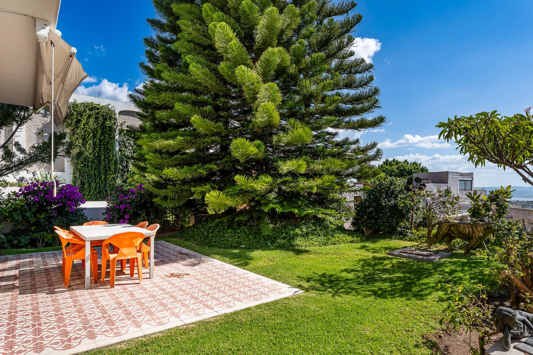 Shared amenity: A garden patio with orange seating beside a large evergreen tree.