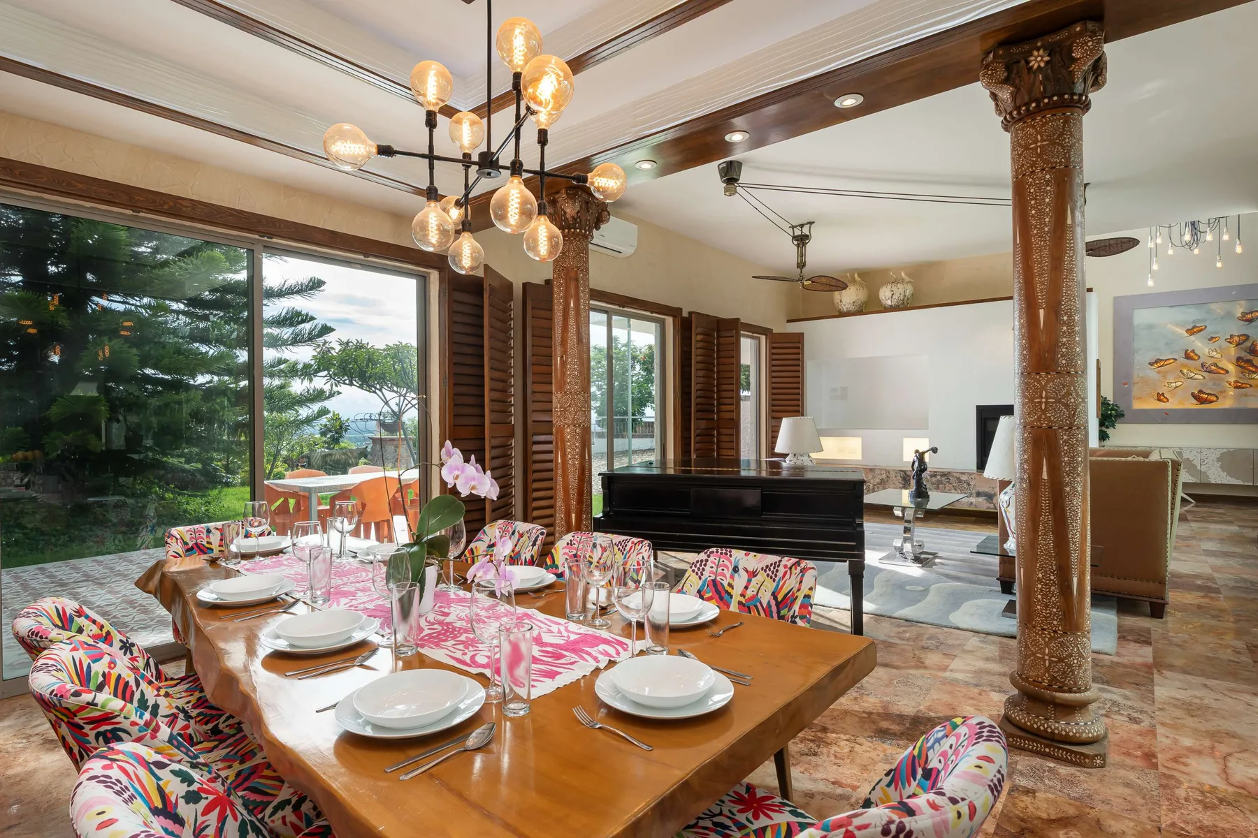 A dining area with a set table beside large windows and a living space.