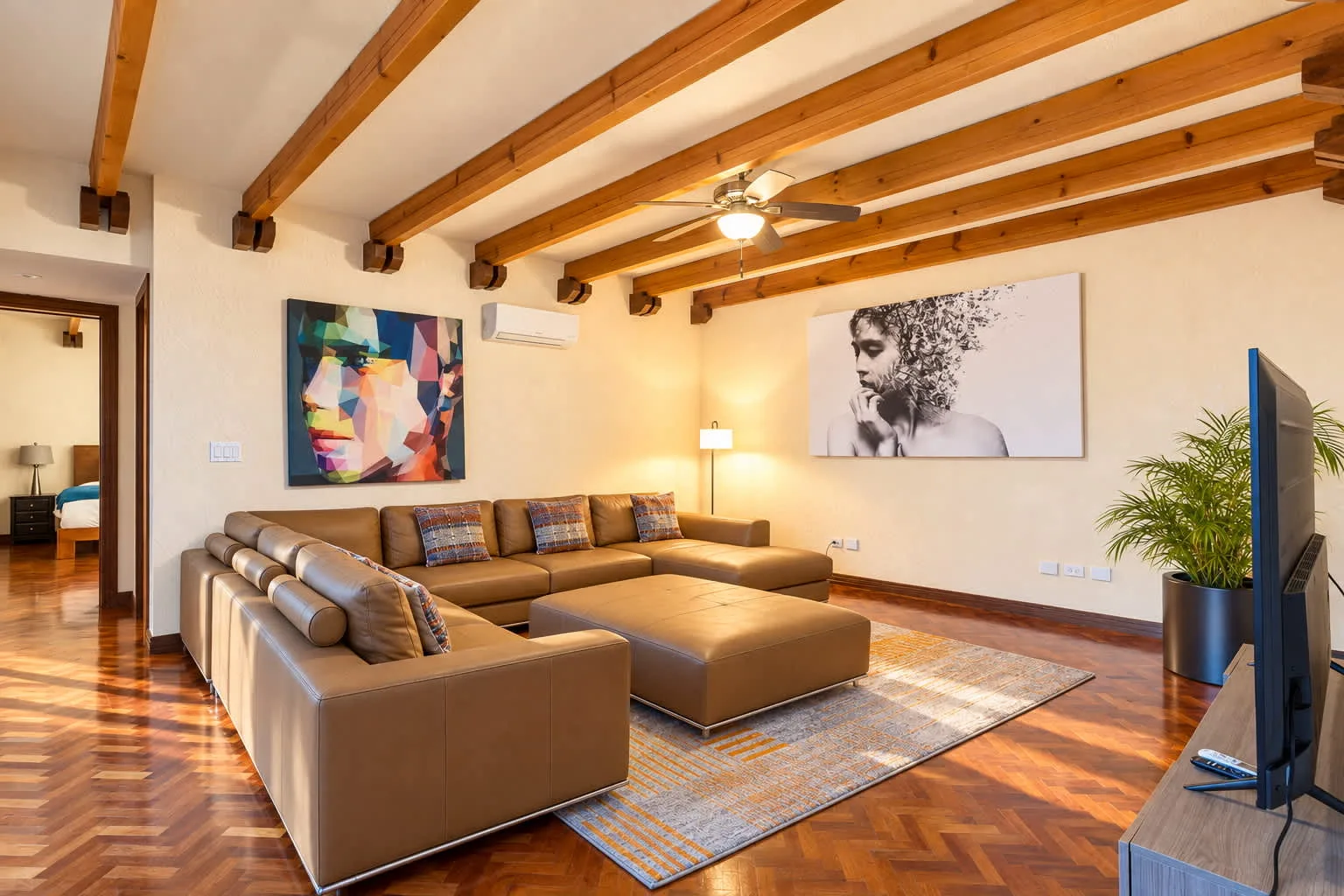 A living room with sectional seating, a rug, and exposed wooden ceiling beams.