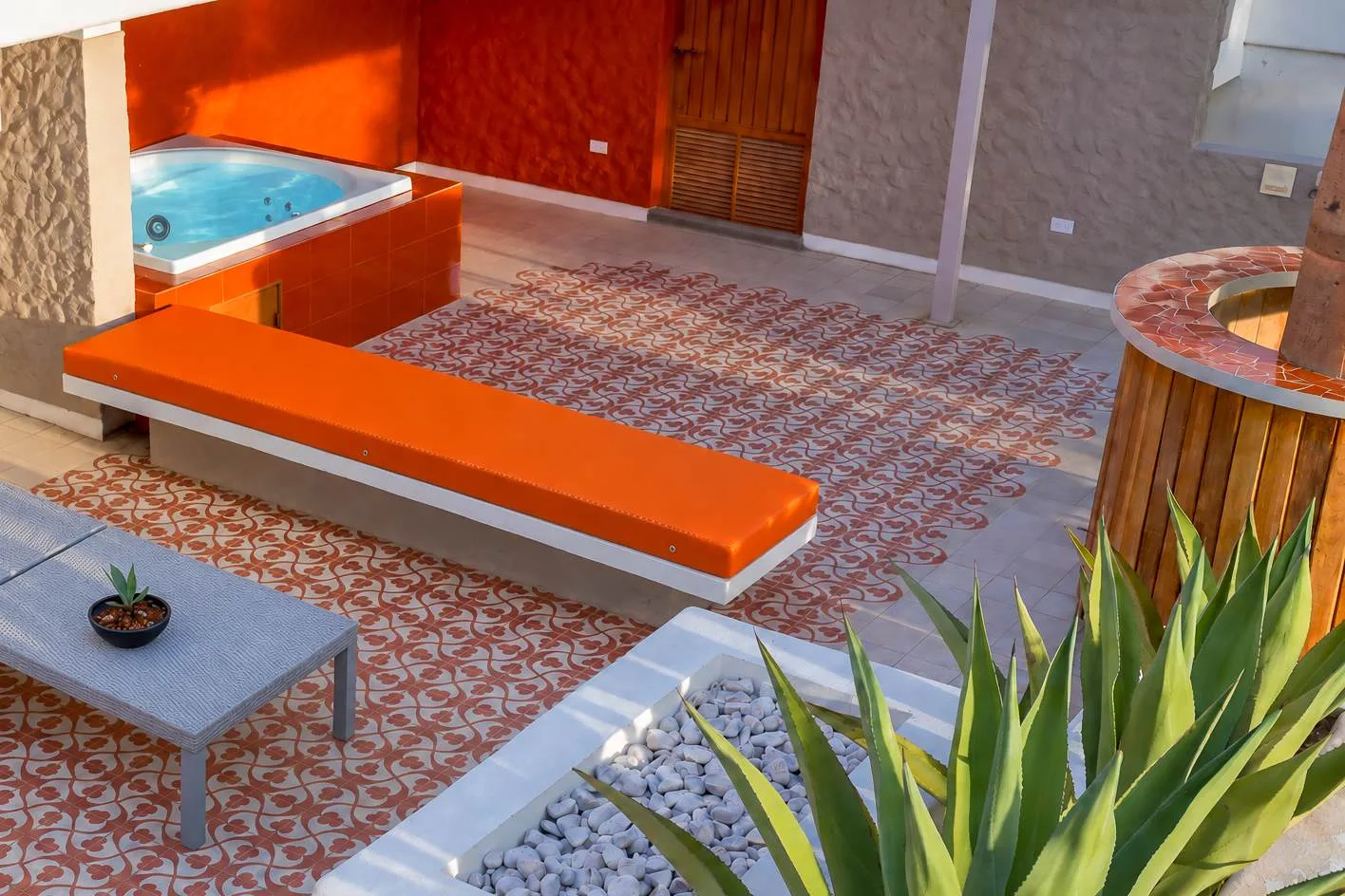 A patterned-tile patio with a bright orange bench and a small turquoise pool.