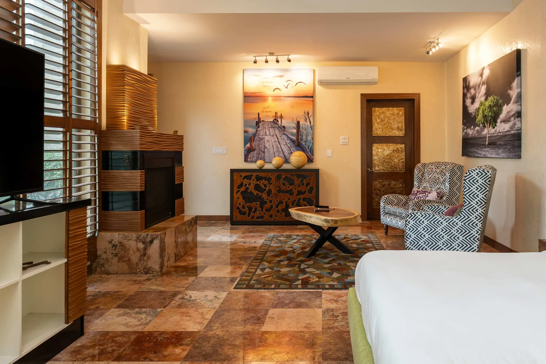 A bedroom sitting area with a bed, two patterned chairs, and a low coffee table.