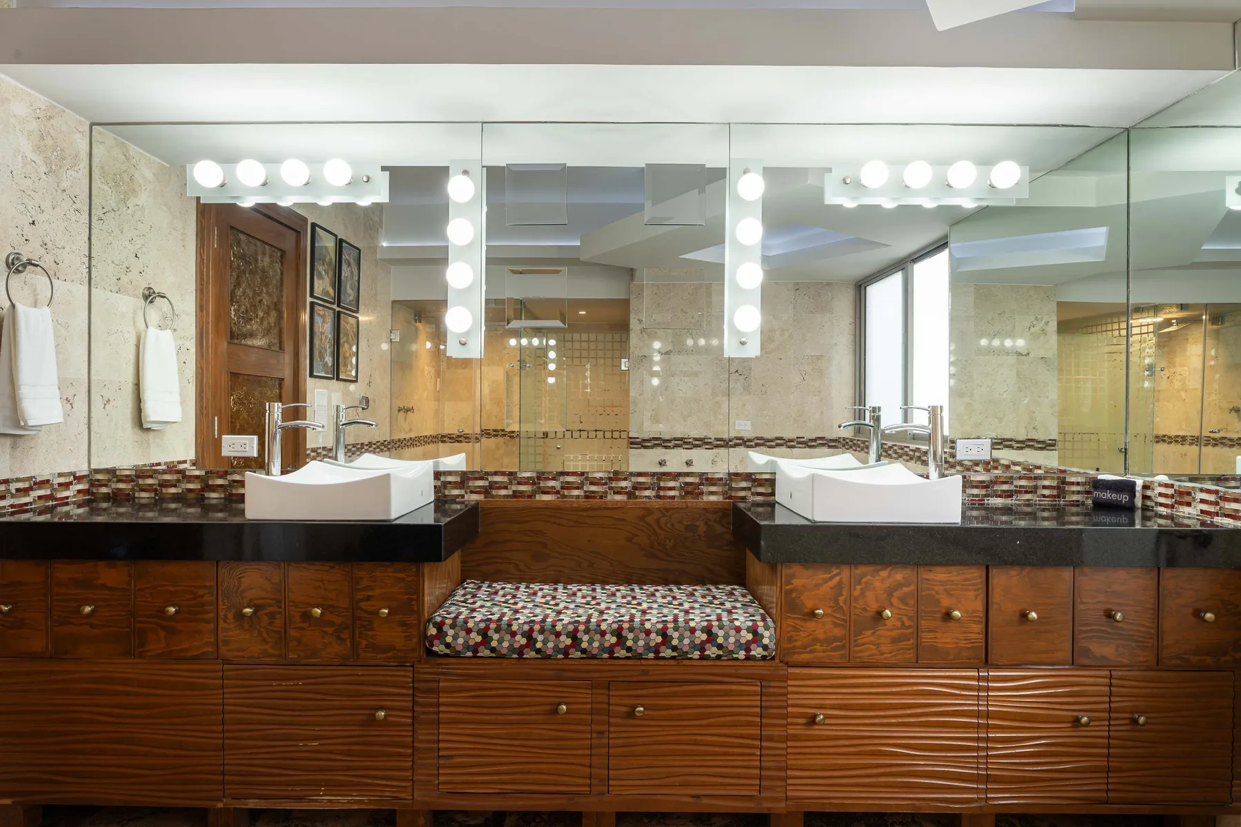A bathroom vanity with two sinks, broad mirrors, and illuminated lights.