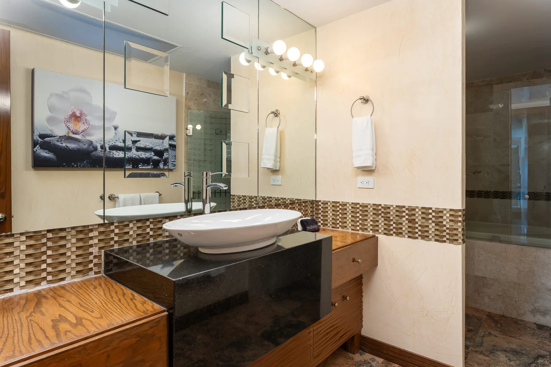 Bathroom with a vessel sink, large mirror, and tiled wall accents.