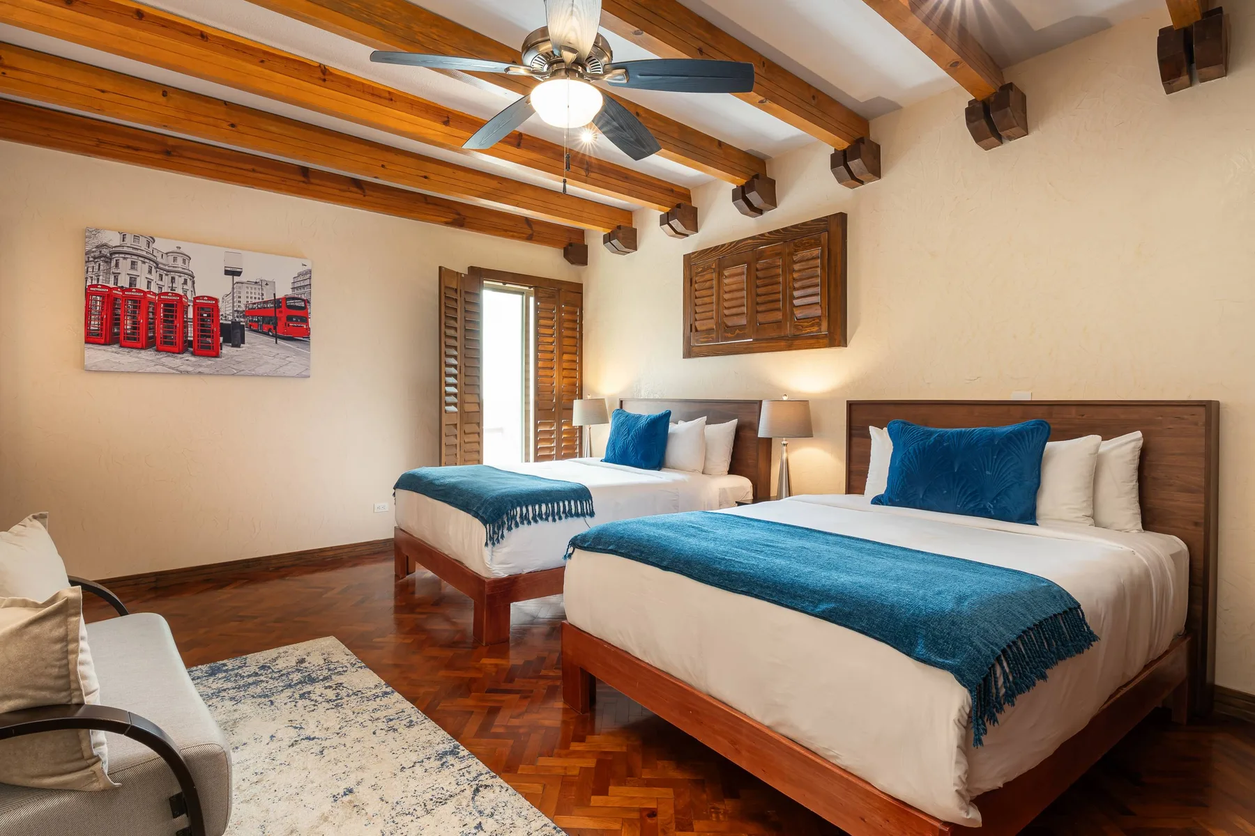A bedroom with two beds dressed in white linens and blue accents.