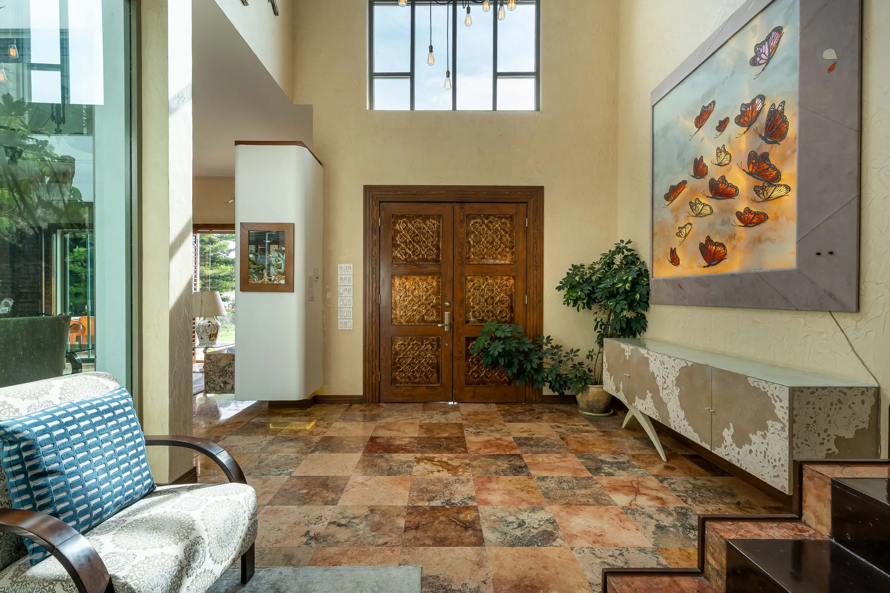 A tall entry hall with ornate wooden double doors and a large wall painting.