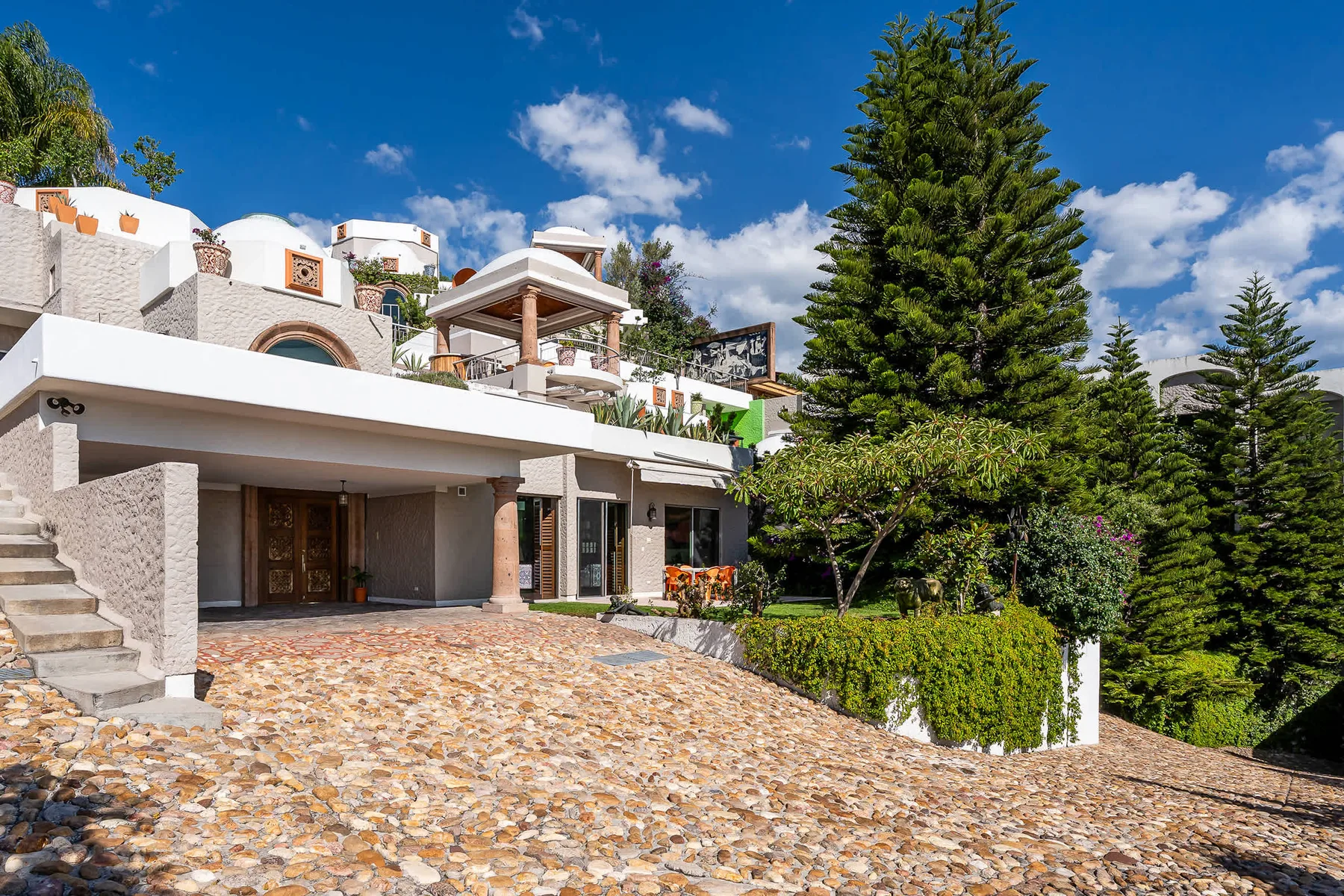 Shared amenity: A multi-level building stands beside a stone-paved driveway and landscaped greenery.
