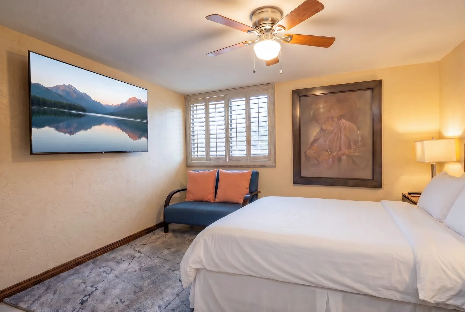 A bedroom with a large bed, a wall-mounted television, and a window.