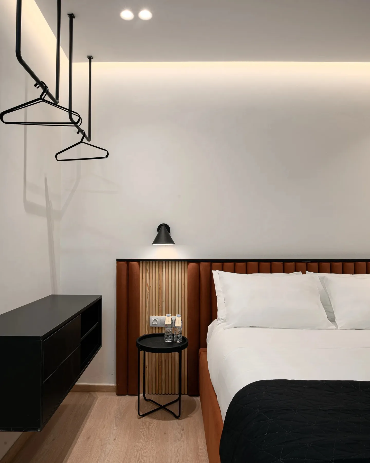A bedroom with a bed, a bedside table, and a wall-mounted lamp.