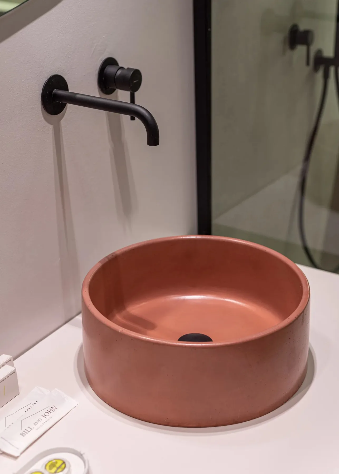 A bathroom vanity with a round terracotta-colored basin and a wall-mounted faucet.