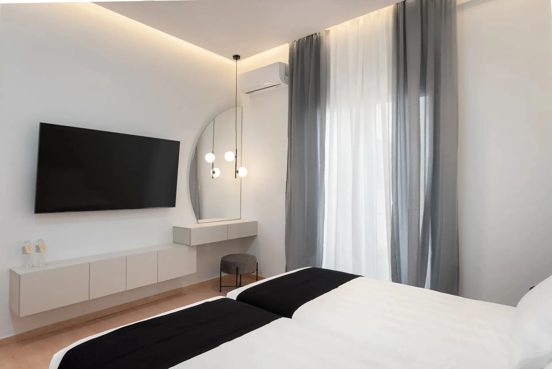 A bedroom with a bed, wall-mounted television, and full-length curtains.
