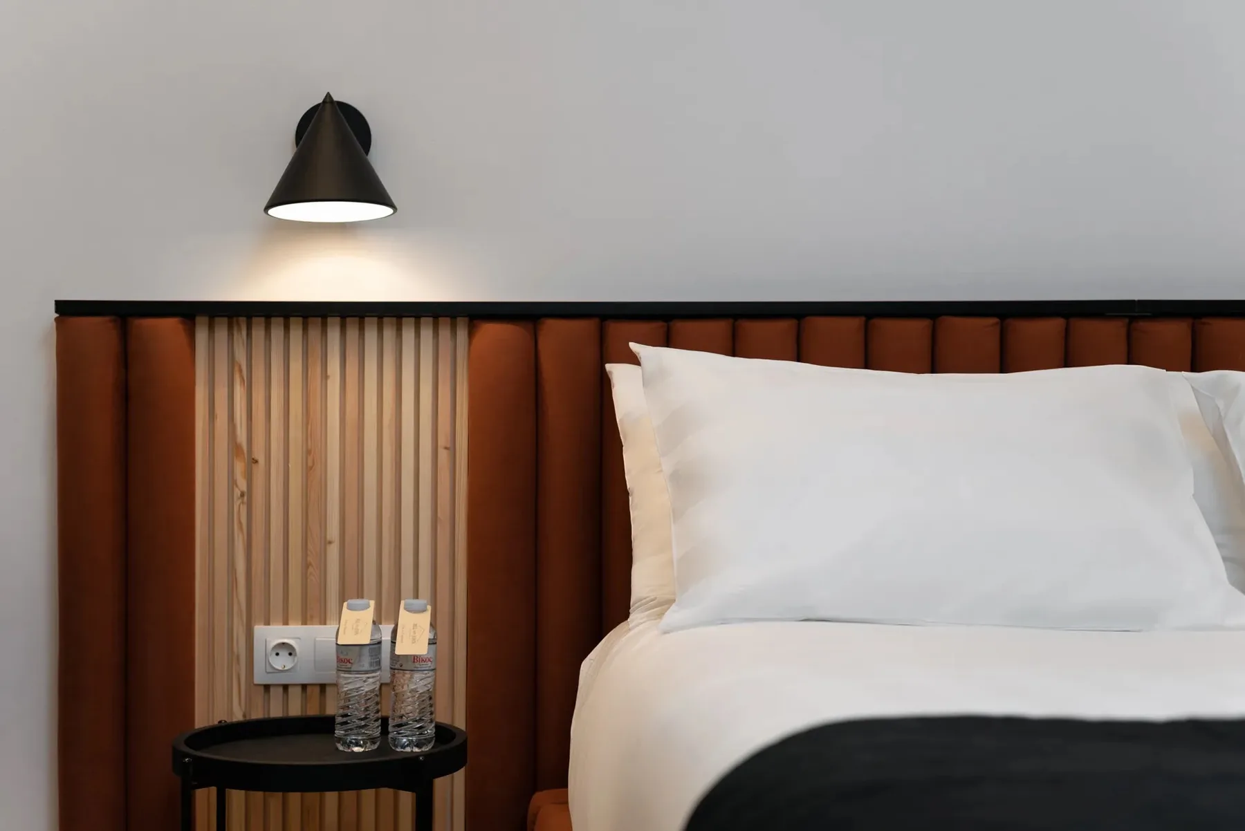 A bedroom with a neatly made bed and a small bedside table.