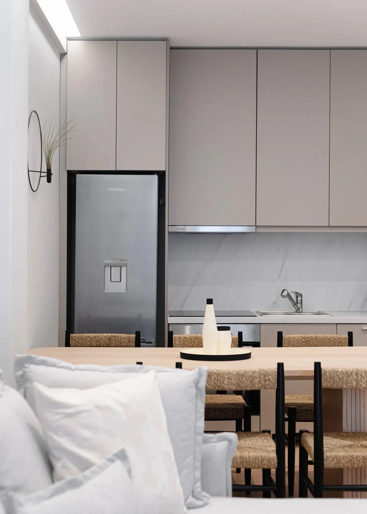 A dining area with a table and woven seating beside a modern kitchen.