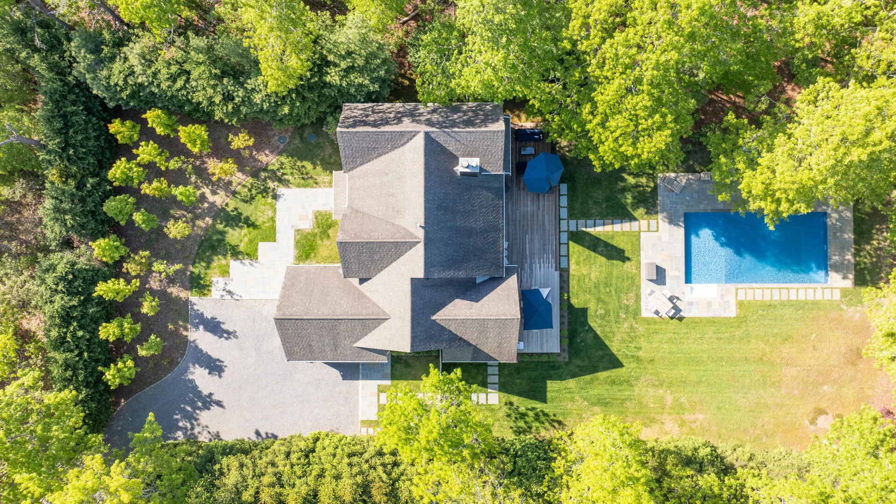 Una vista aérea muestra una casa, una piscina y árboles alrededor.