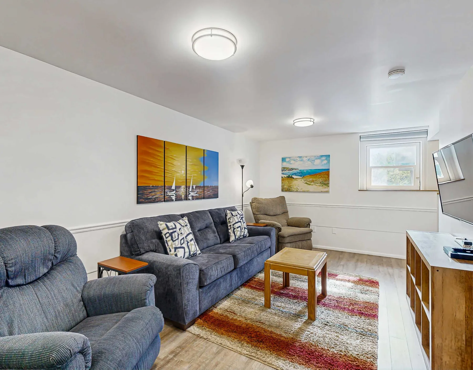 A living room with seating, wall art, and a rug around a coffee table.