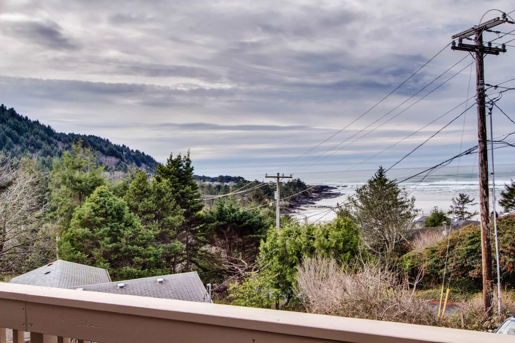 A coastal landscape with wooded hills, ocean views, and utility lines.