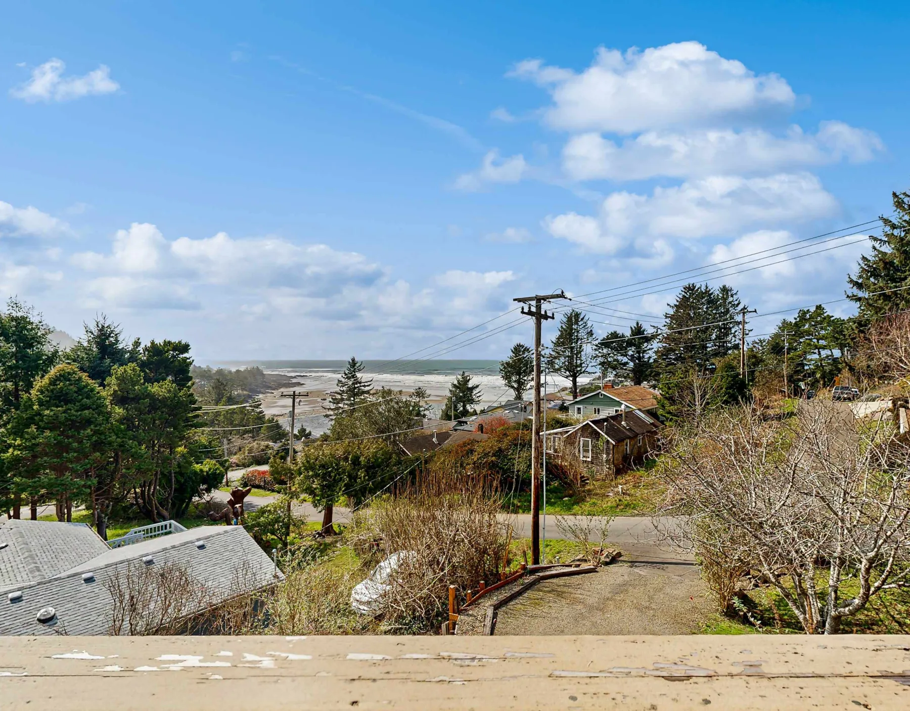 A coastal neighborhood sits below a partly cloudy sky, with water visible in the distance.
