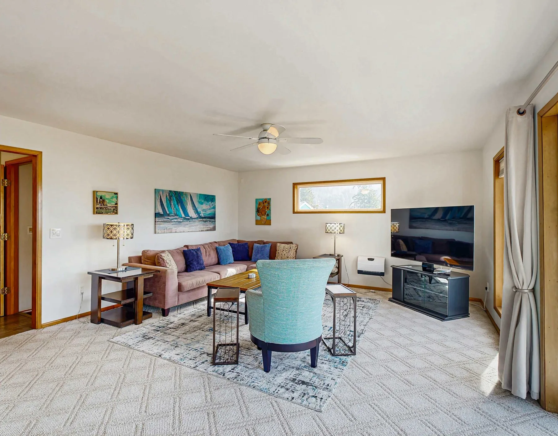 A living room with seating arranged around a rug and a television.