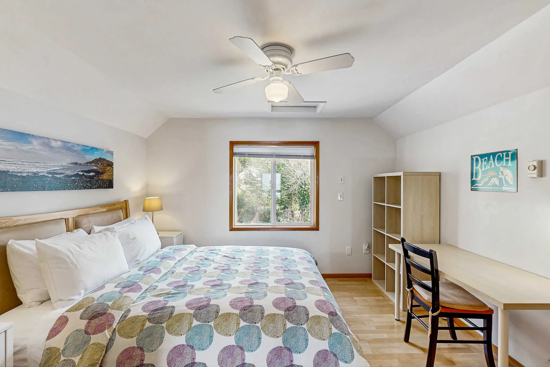 A bedroom with a bed, a window, and a desk with a chair.