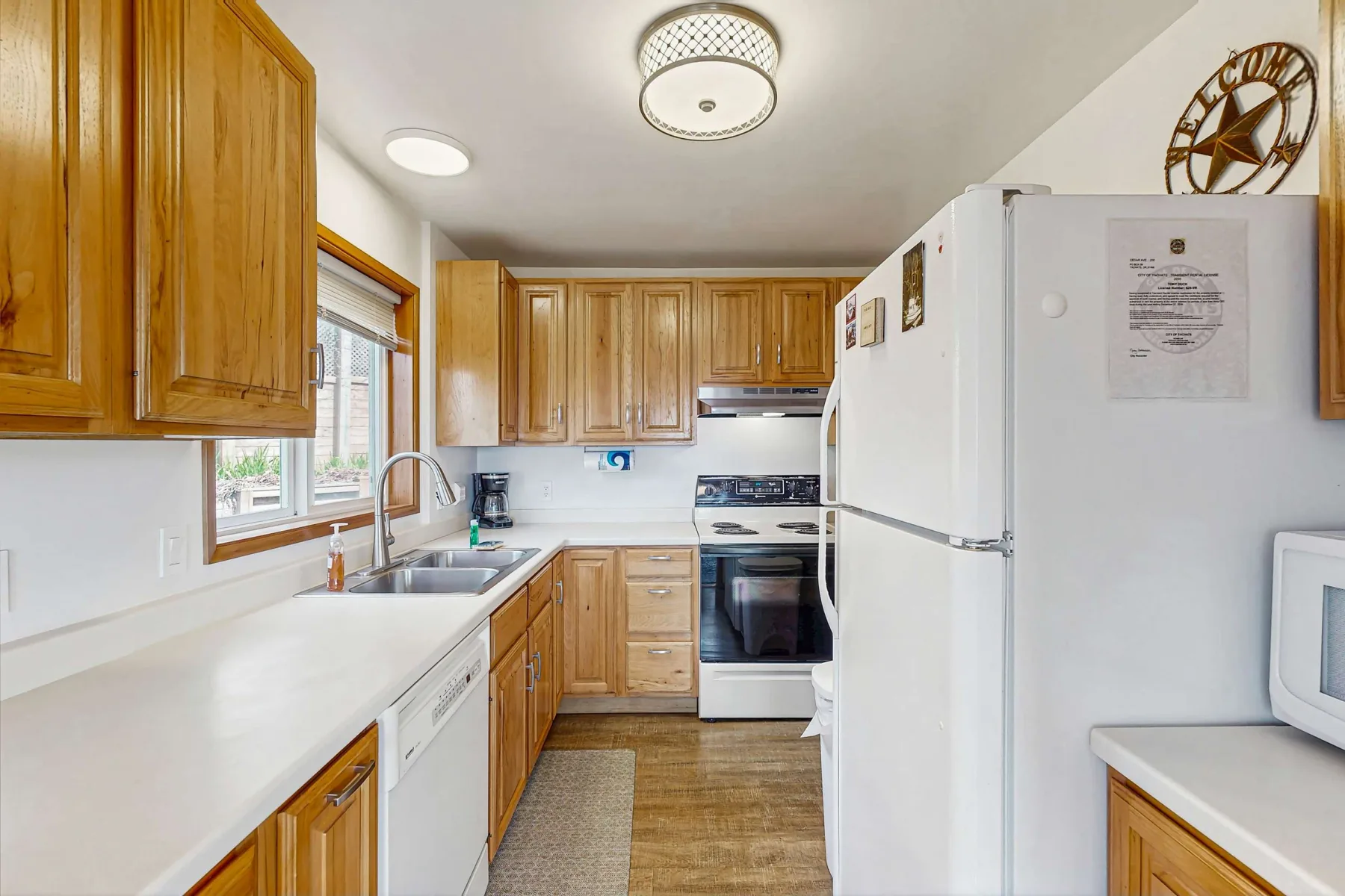 A kitchen with wooden cabinets, white countertops, and a refrigerator.