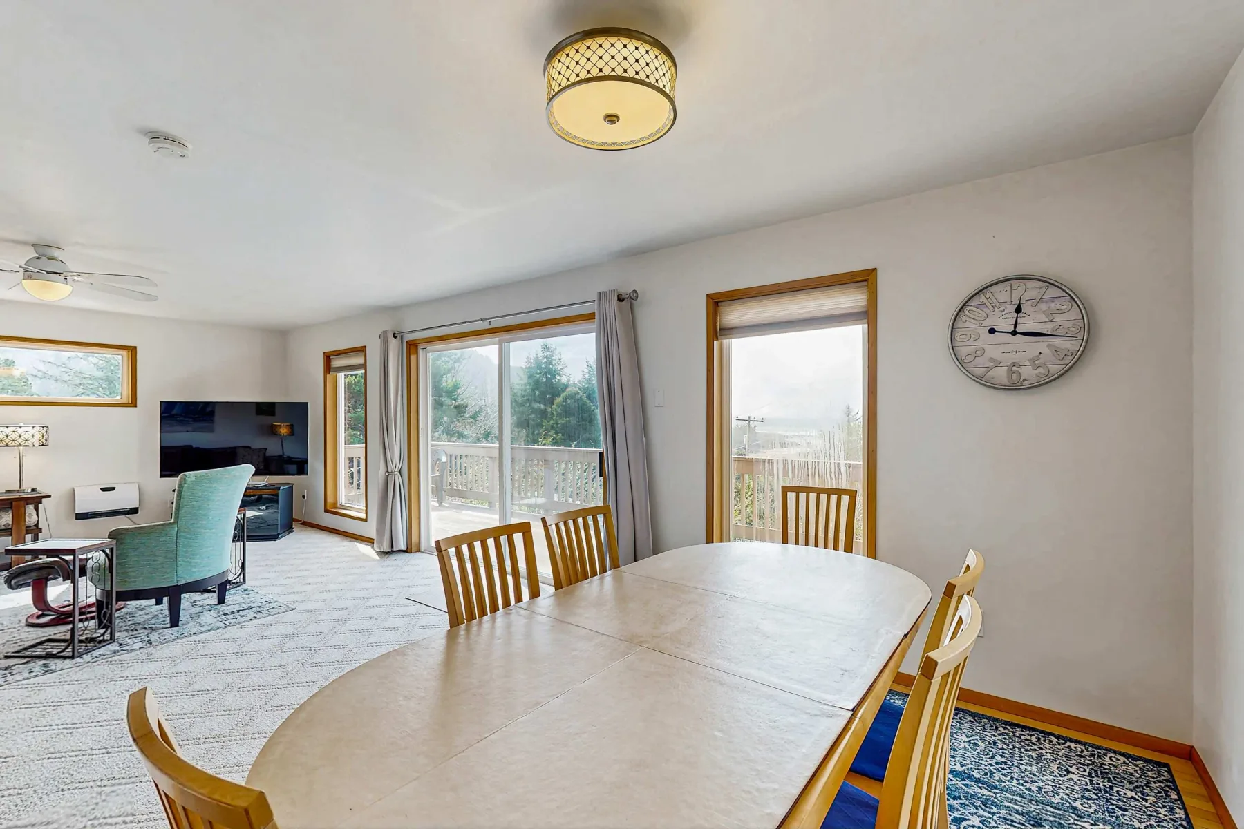 A bright dining area opens onto a living space, with large windows overlooking the outdoors.