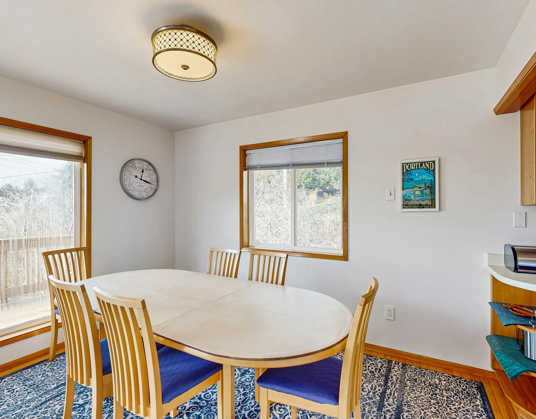 A dining room with a light-colored table and seating on a patterned rug.