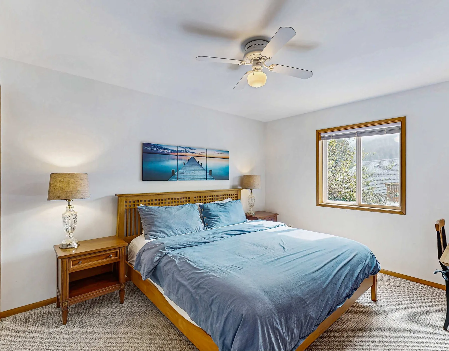 A bedroom with a bed beneath a ceiling fan and a window.