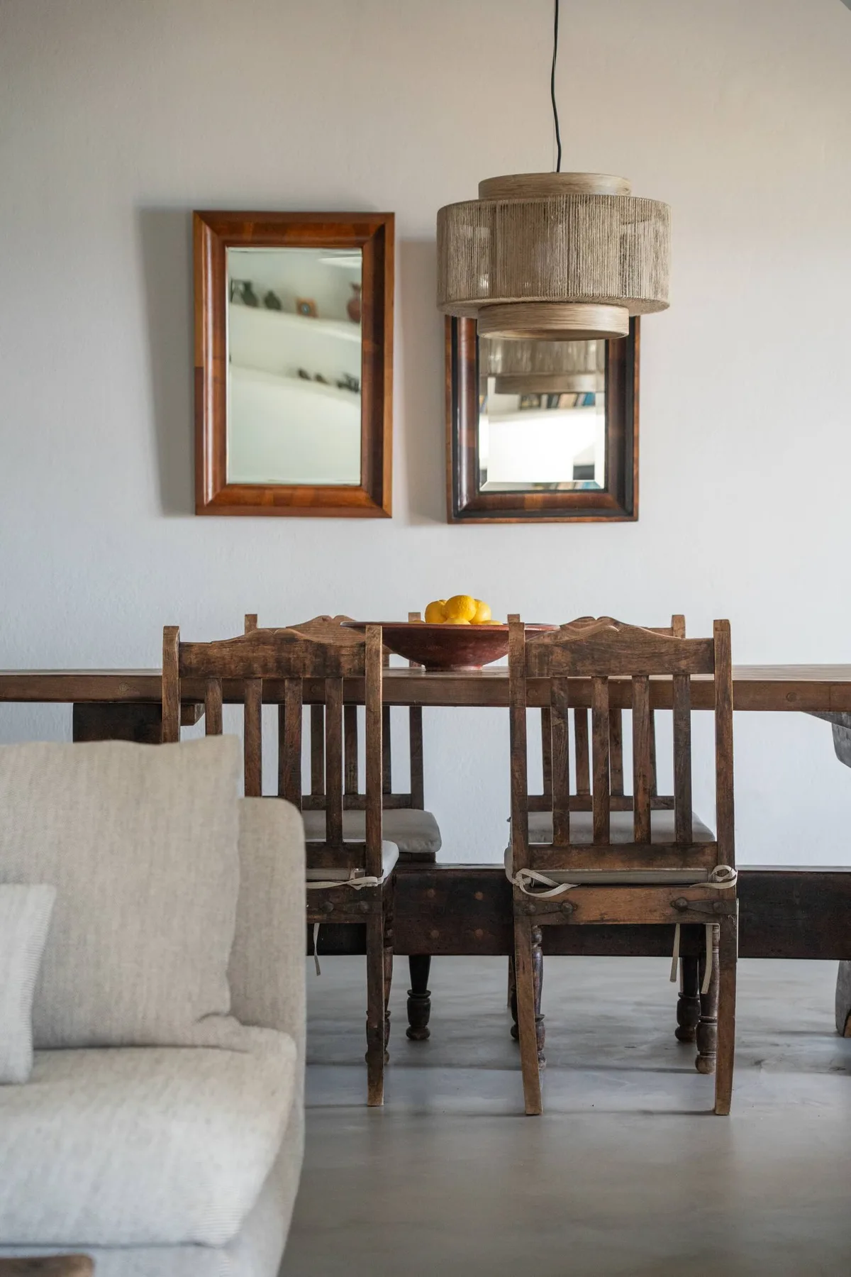 A dining area with a wooden table, seating, and mirrors on the wall.