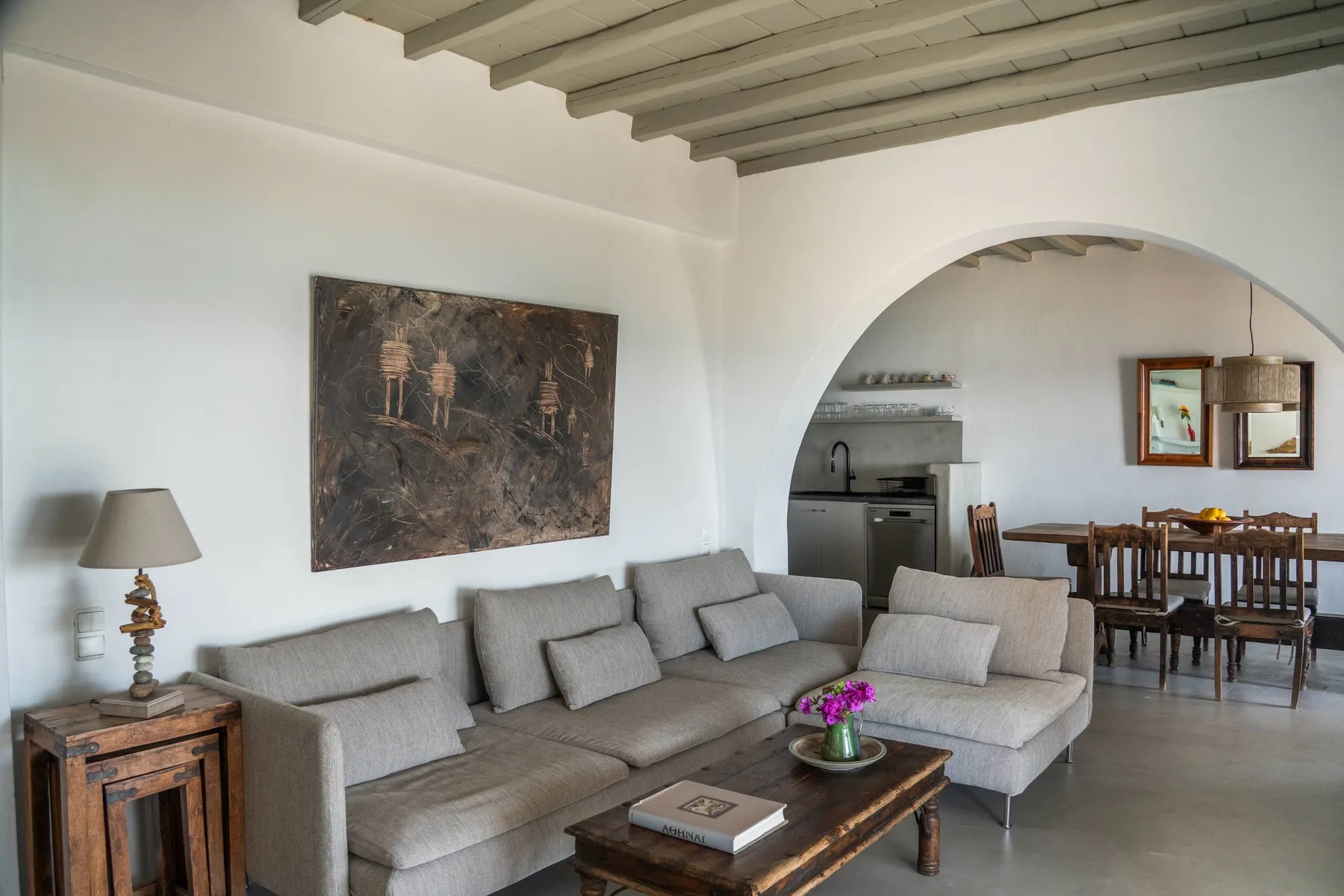 A living room with a sectional seating area and an arched opening to the dining space.