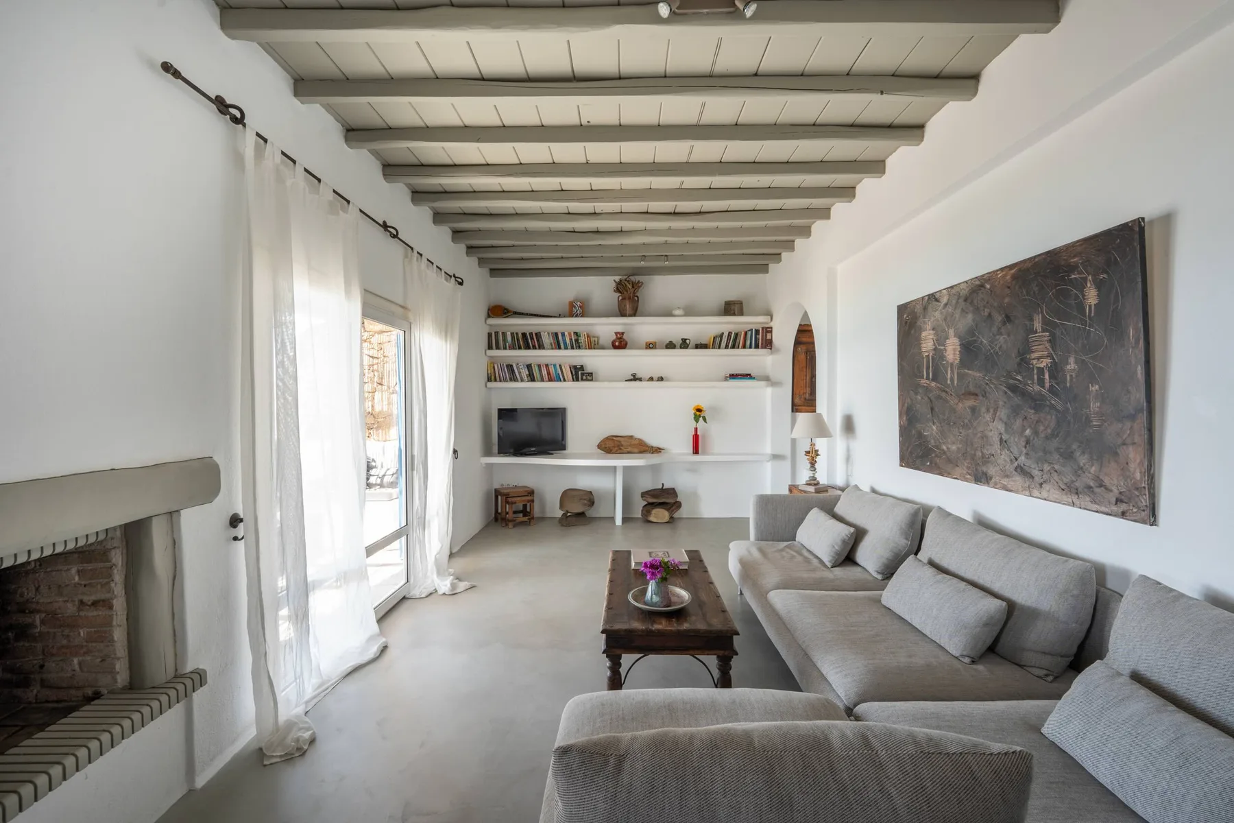 A bright living room with a sectional sofa, coffee table, and large wall artwork.