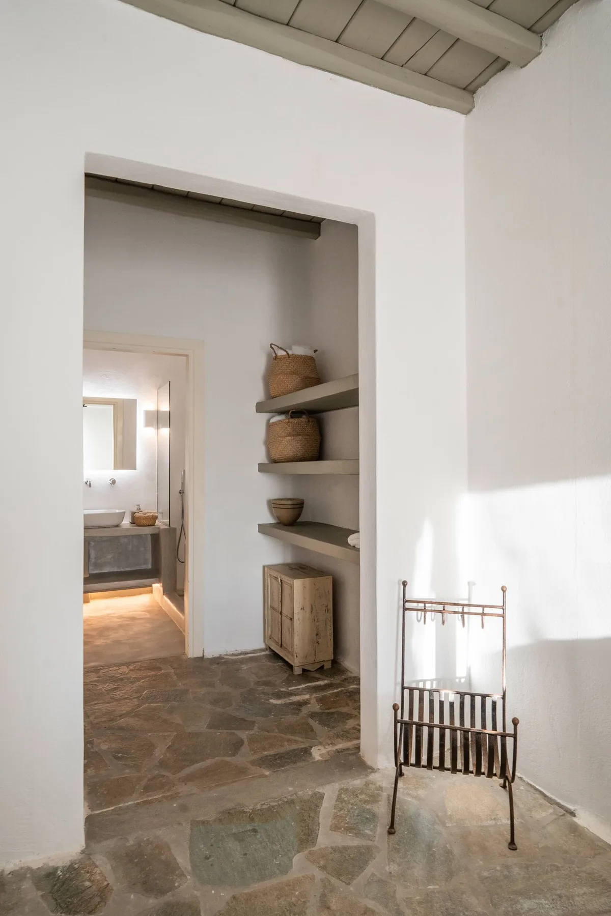 A bright interior hallway with open shelves and stone flooring.