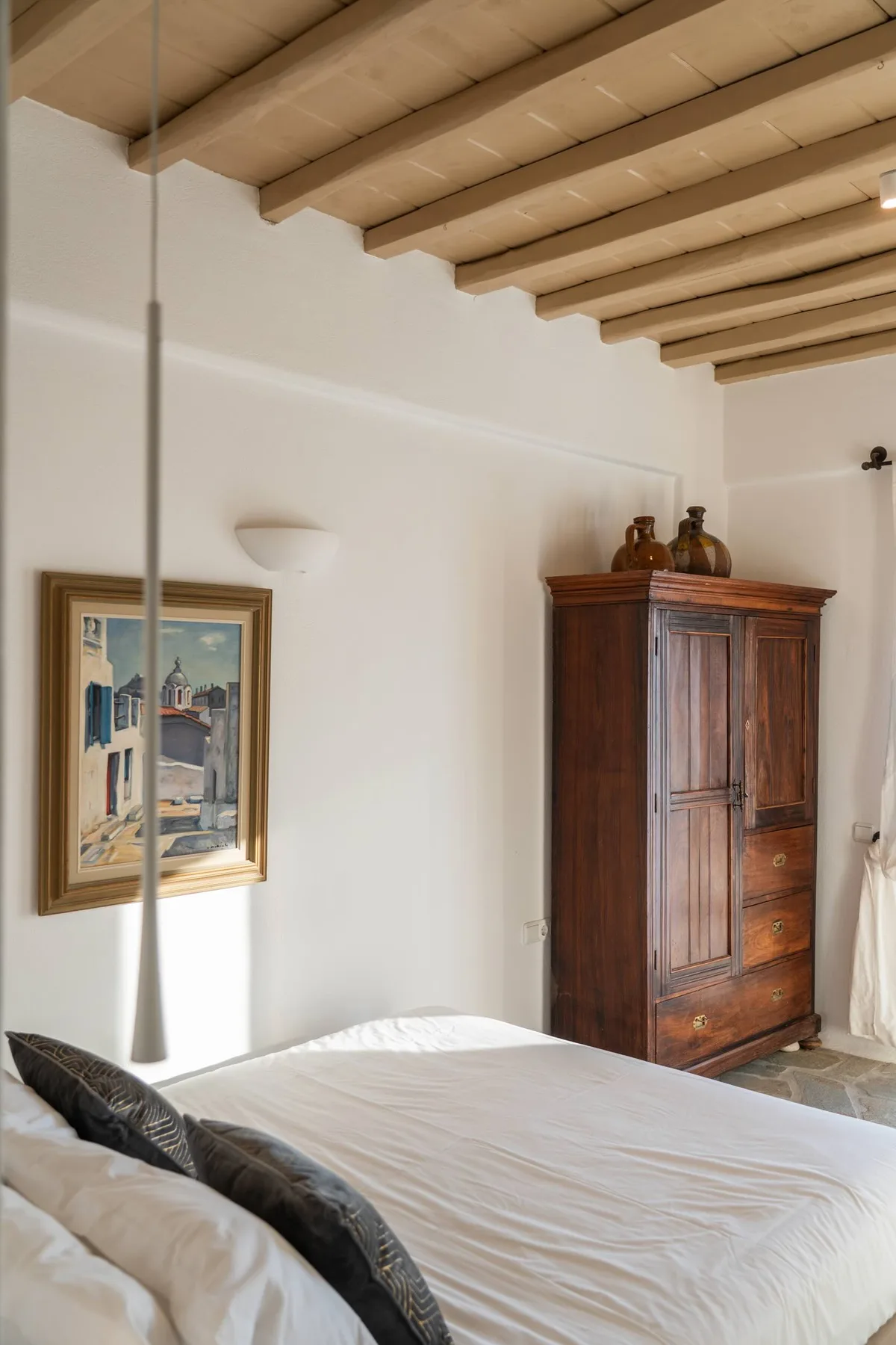 A bedroom with a neatly made bed and a wooden wardrobe.