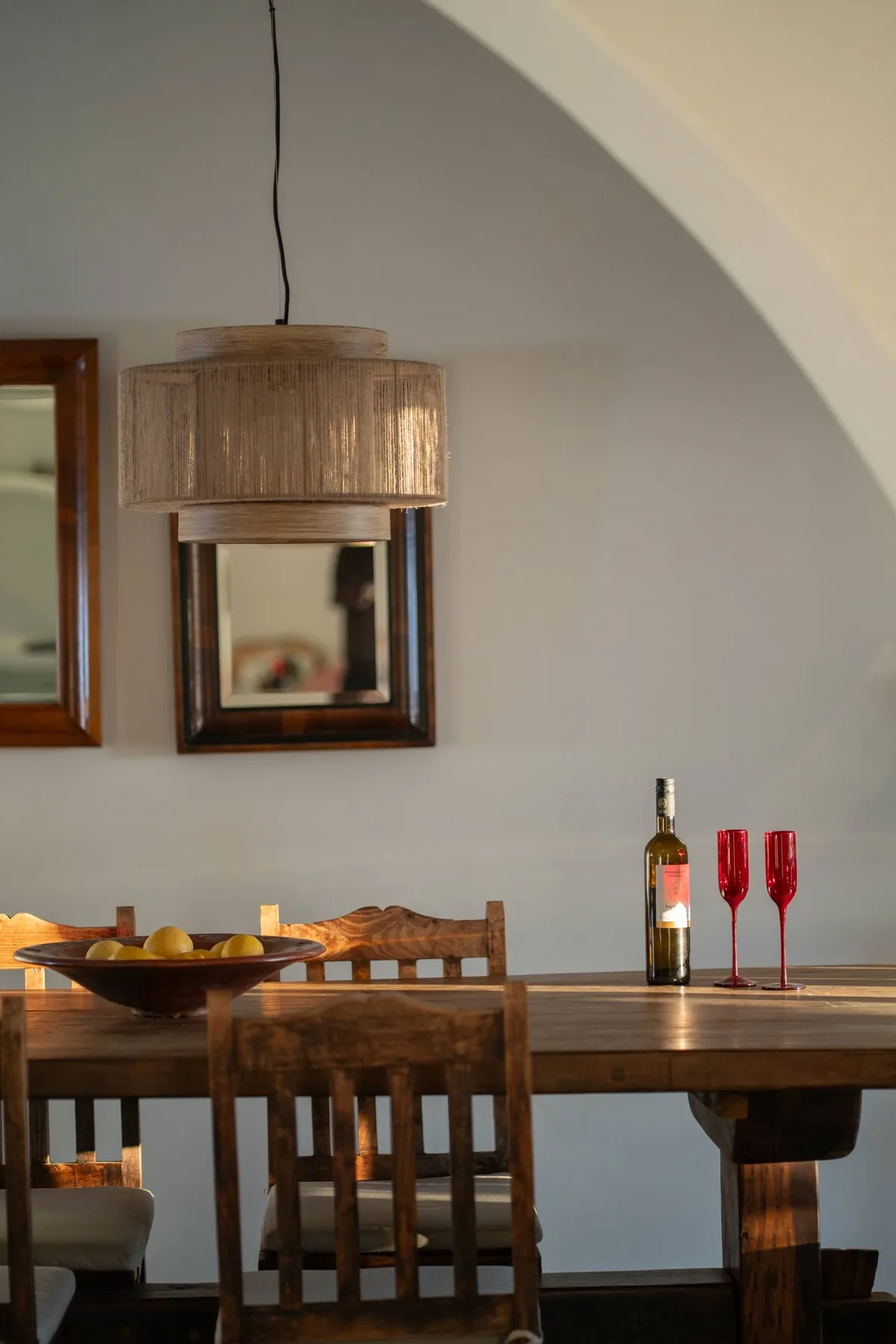 A dining area with a wooden table, chairs, and a hanging lamp.