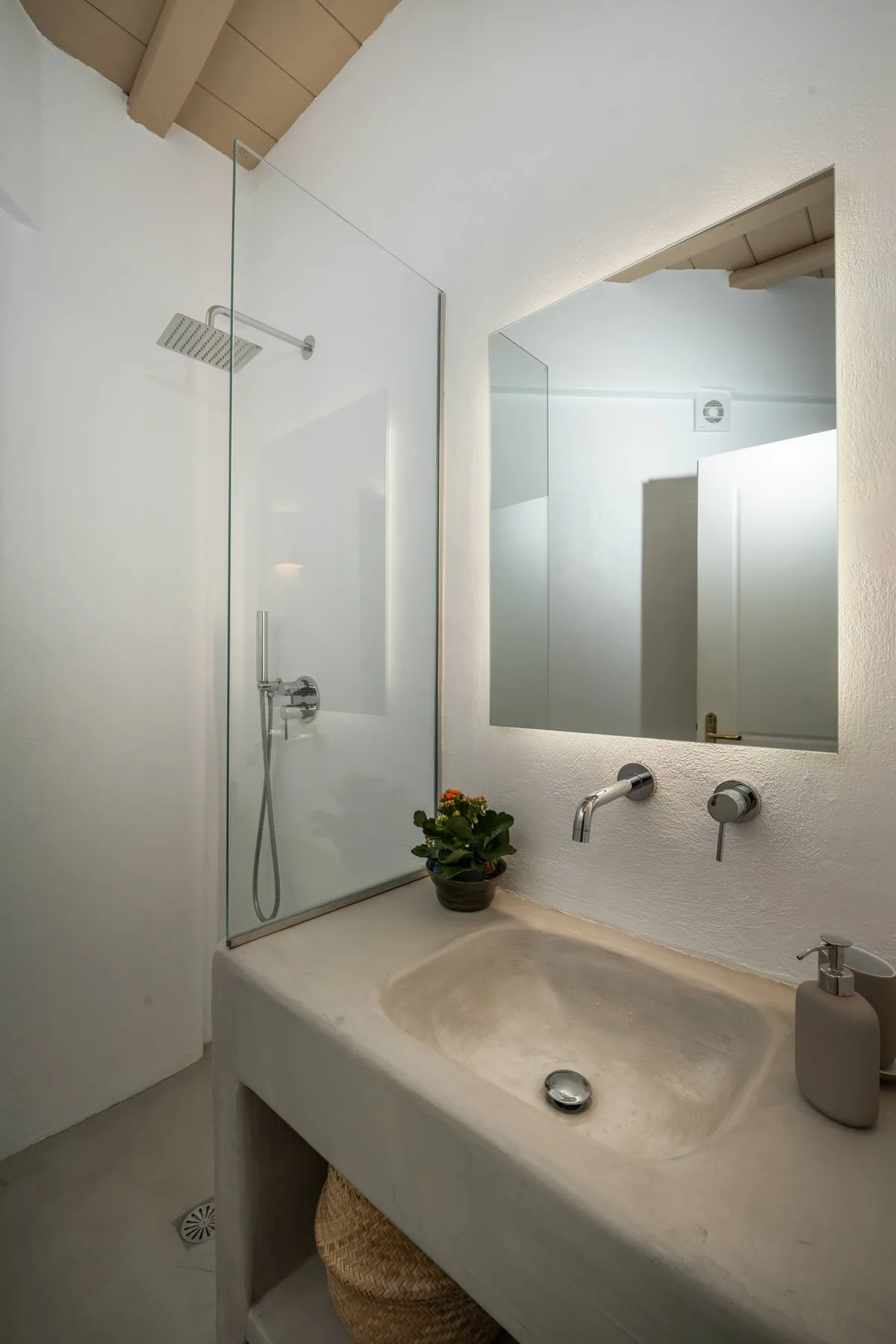 A bright bathroom with a glass shower, wall mirror, and broad sink.