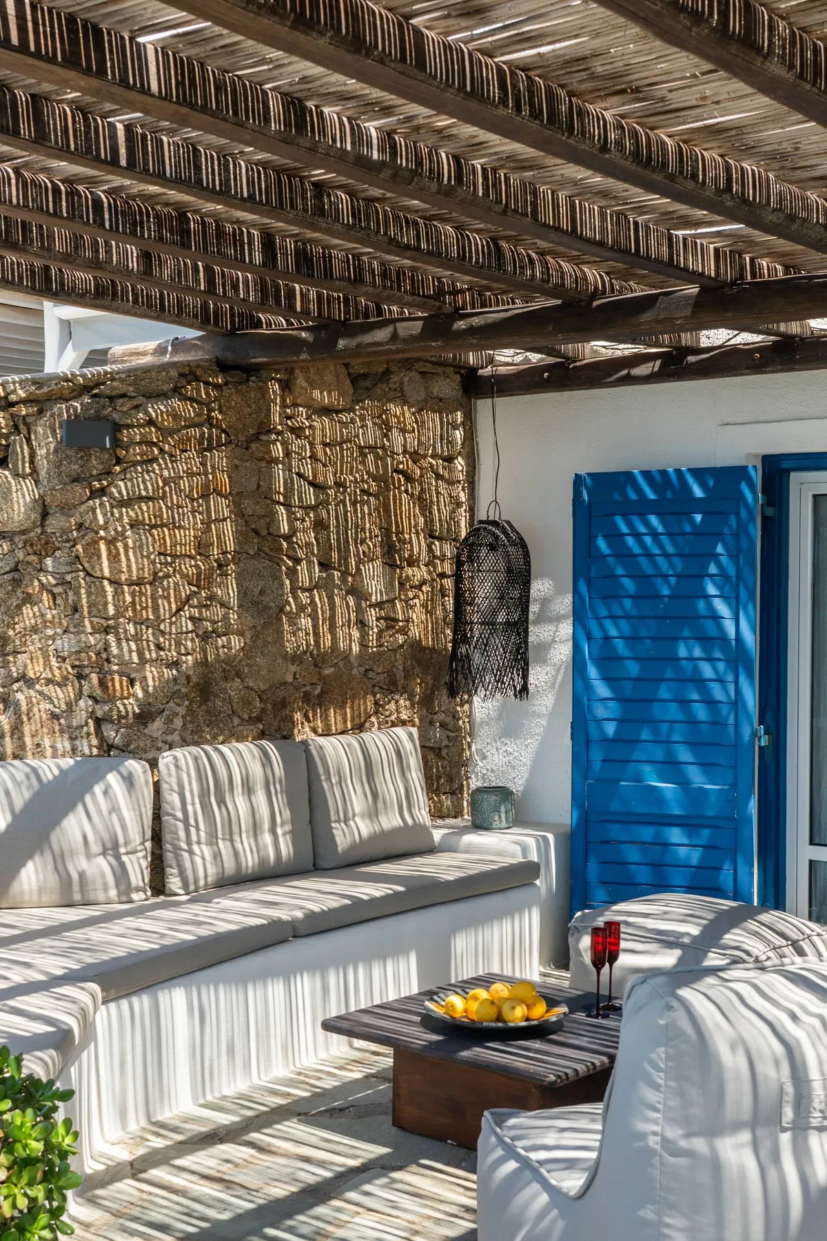 A shaded outdoor seating area with white cushions and a low table.
