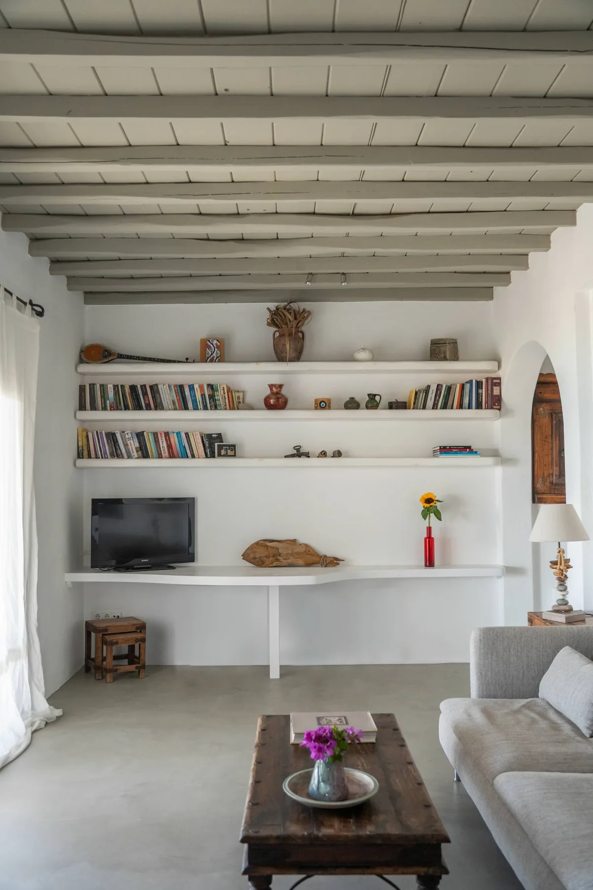 A bright living room with built-in shelves, a television, and seating.