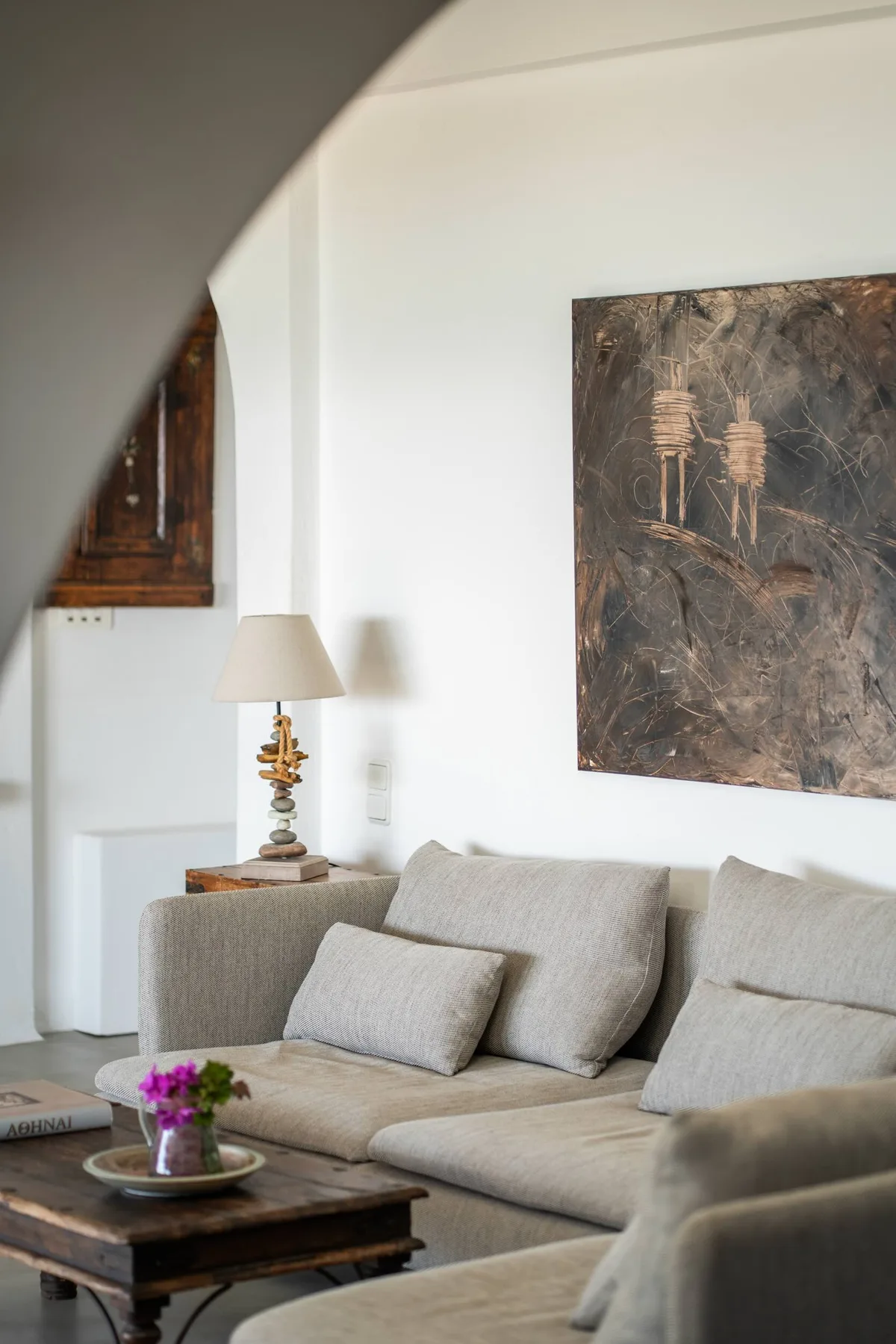 A living room with a sectional sofa, coffee table, and large wall artwork.