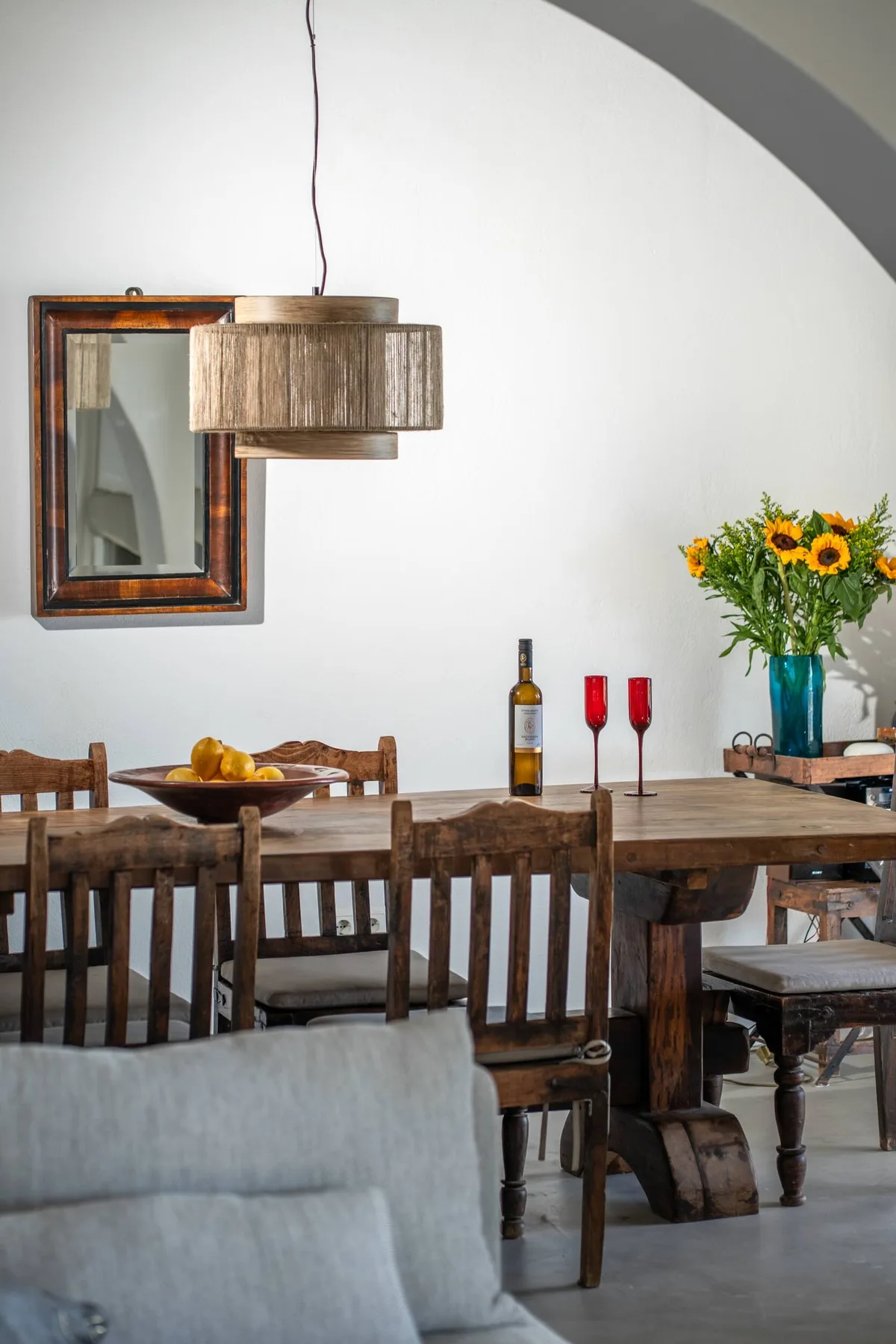 A dining area with a wooden table, chairs, and a vase of sunflowers.