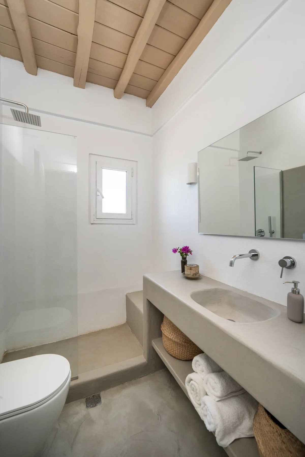 A bright bathroom with a walk-in shower and a long vanity.