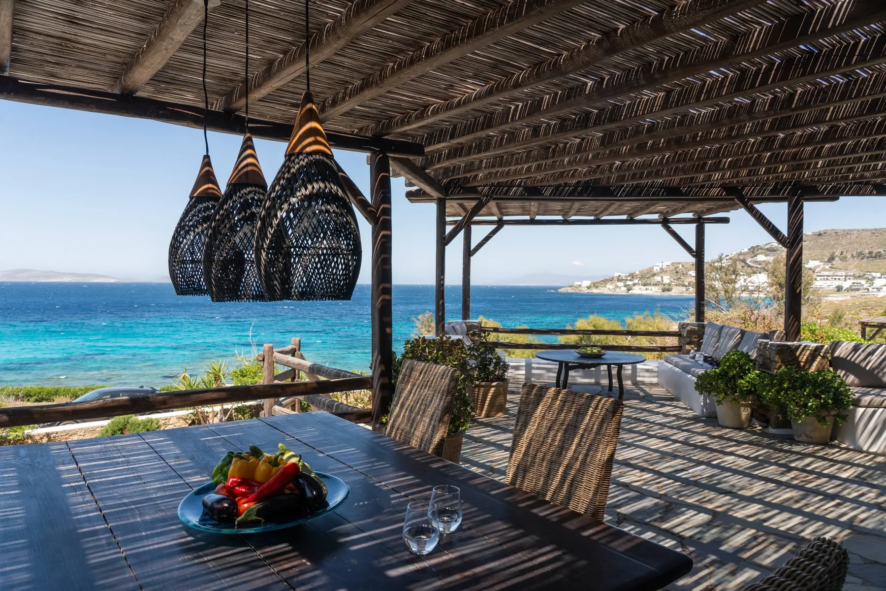 A shaded seaside dining terrace overlooks the blue ocean.