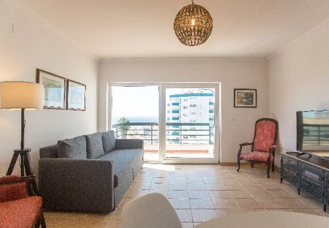 Una sala de estar con asientos grises y puertas de vidrio que dan a un balcón.