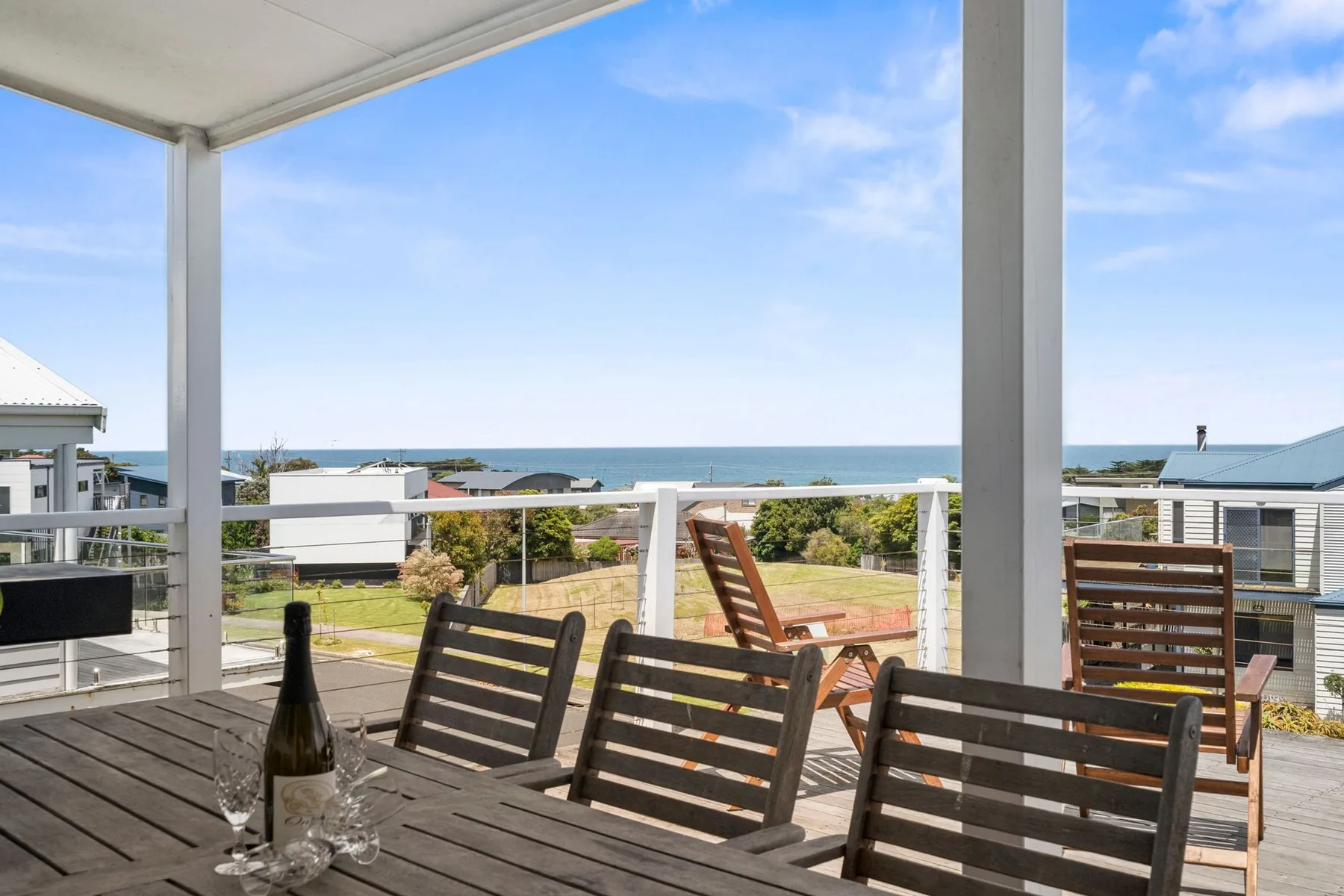 A covered outdoor deck overlooks nearby houses and the ocean.